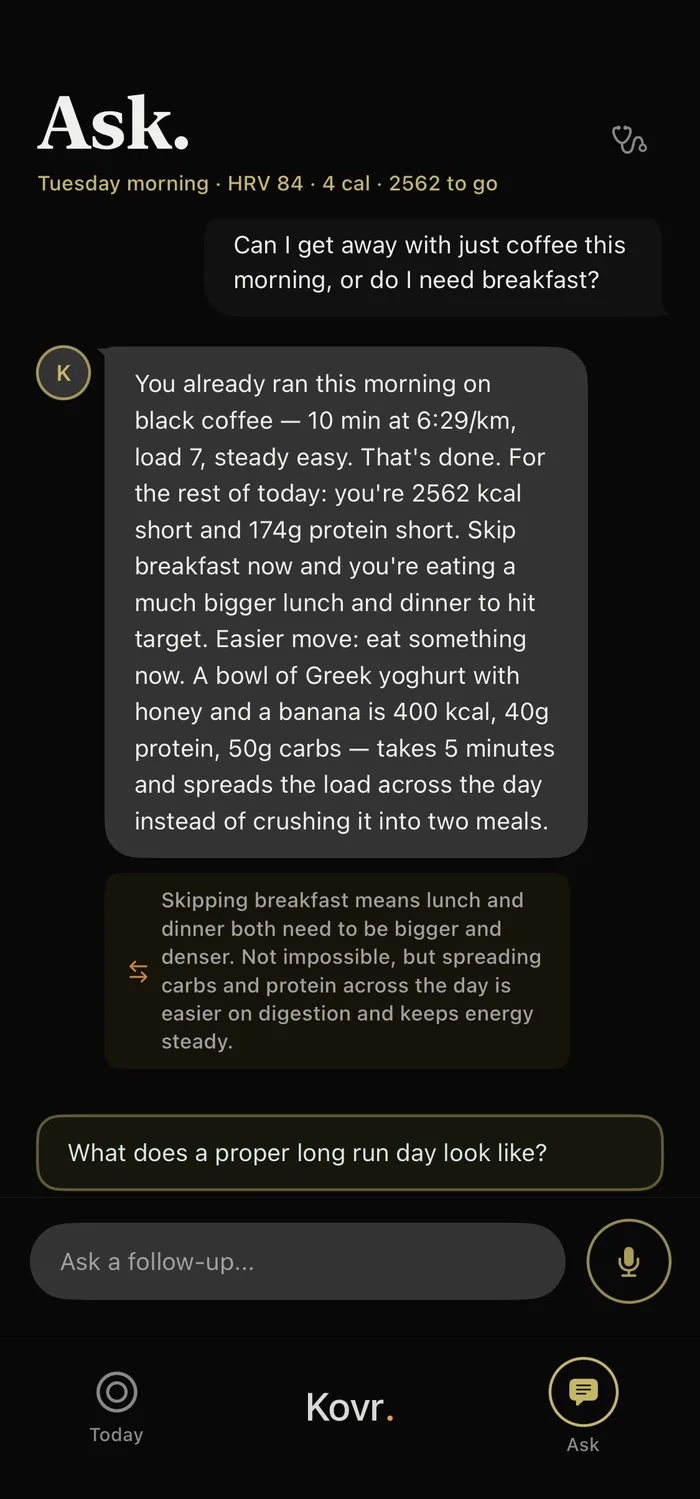 Kovr Ask screen on a Tuesday morning, HRV 84. The athlete asks whether coffee alone is enough or breakfast is needed; Kovr replies that the morning run is already done on black coffee, the day is 2,562 kcal and 174g protein short, and suggests Greek yoghurt with honey and a banana now rather than crushing two big meals later, with a note on the trade-off it weighed.